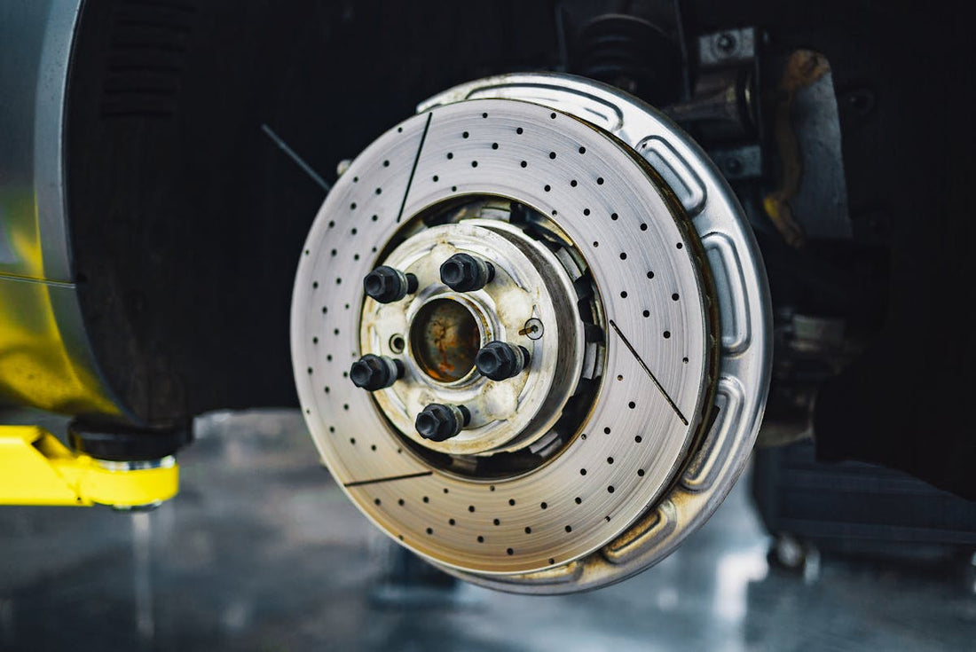 Close-up of a performance cross-drilled brake rotor and hub during a Tesla brake service