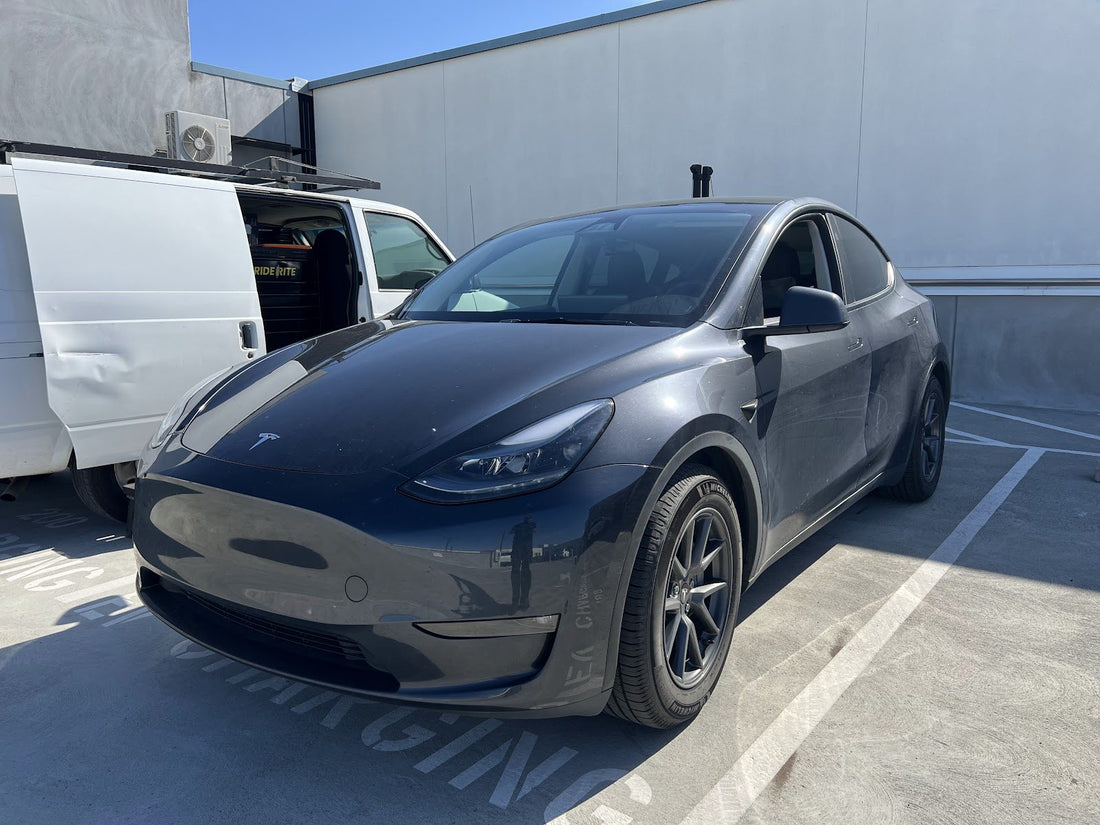 Gray Tesla Model Y parked next to the Ride Rite mobile service van before a Tesla shock inspection