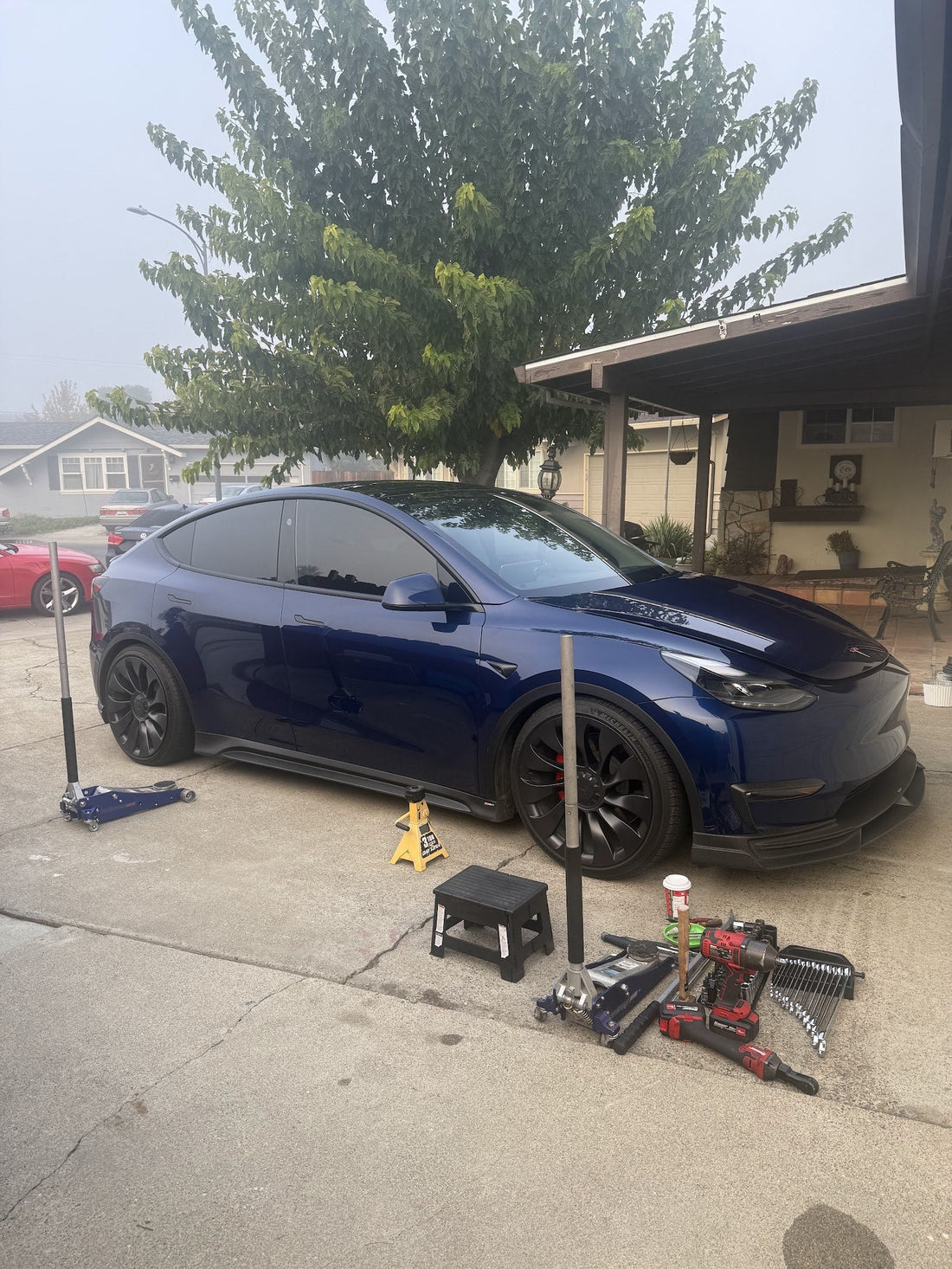 Blue Tesla Model Y on jack stands in a San Jose driveway during mobile suspension service